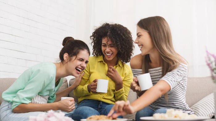 Best friends drinking tea, eating cookies and talking at home