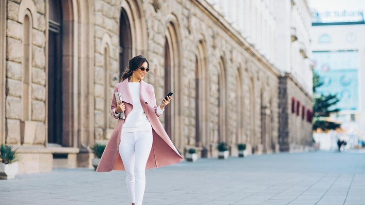 Ilustrasi stylish Elegant young woman walking on the square and texting in urban environment.