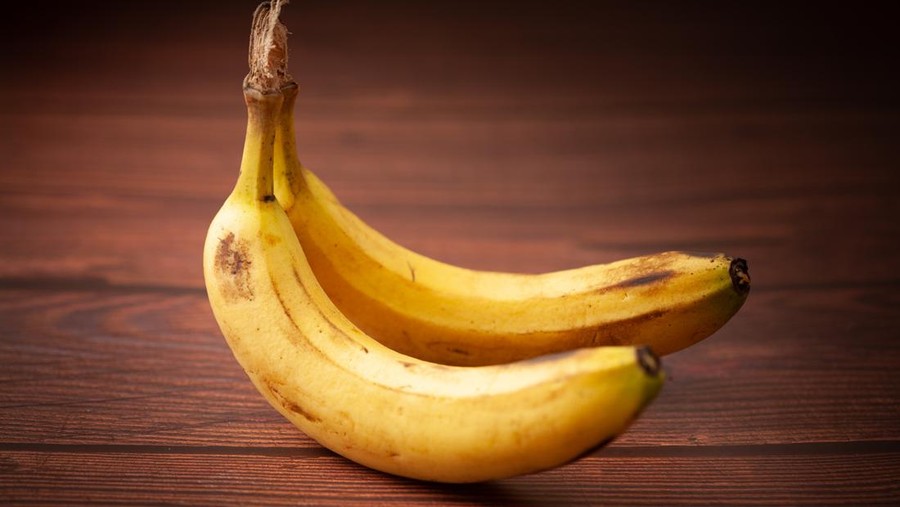 Close-up of two ripe banana (Musa sp) fruits over the wooden background.