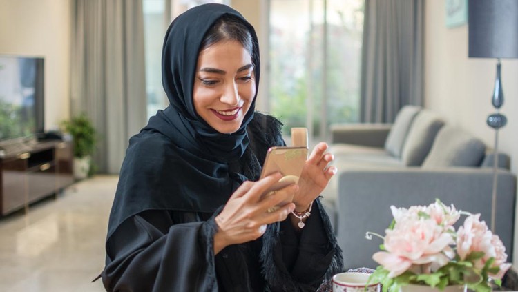 Portrait of smiling arabian girl using mobile phone at home