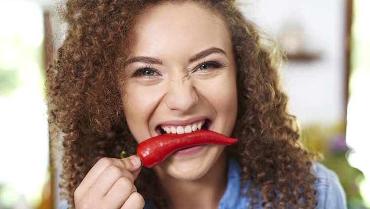 Woman holding red pepper in her mouth