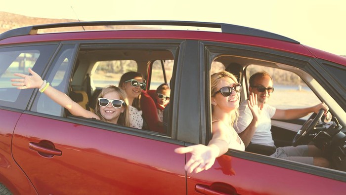 Happy smiling family with daughters in the car with sea background. Portrait of a smiling family with children at beach in the car. Holiday and travel concept