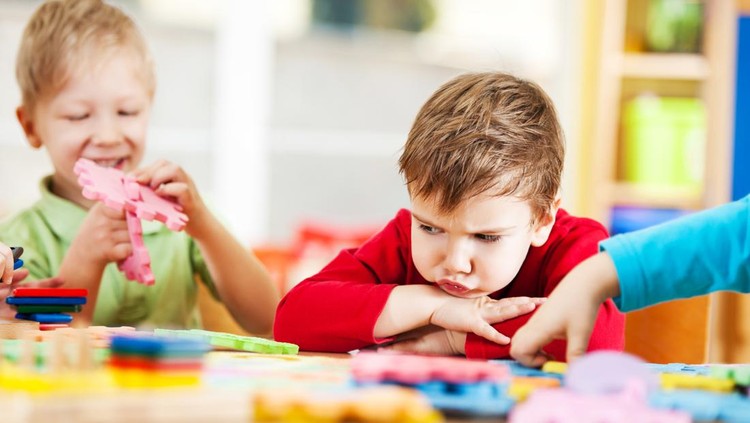 Small angry looking boy looking at the toys.