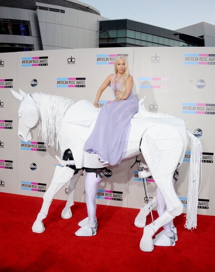 Bukan cuma dari segi pakaian, perempuan bernama lengkap Stefani Joanne Angelina Germanotta membuat prosesi kehadirannya bagaikan performa. Misalnya pada AMA 2013 di mana ia menunggangi kuda mekanik di red carpet. Foto: pinterest.com/Fashionista.com
