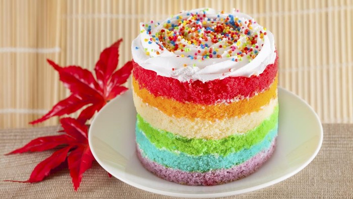 Colorful rainbow cakes on white plate with red maple leaf.