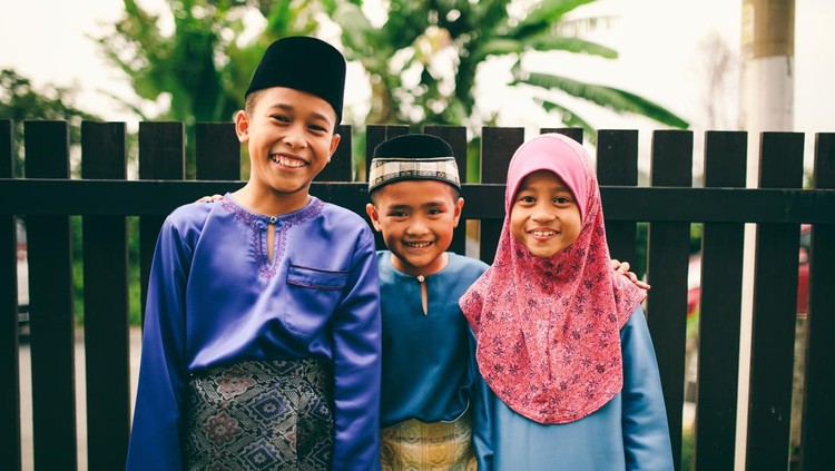 Three sibling playing in front of house during eid celebration in Malaysia