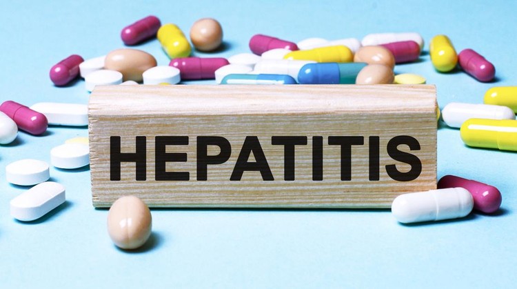 The word Hepatitis is written on wooden blocks next to tablets on a blue background. Medical concept