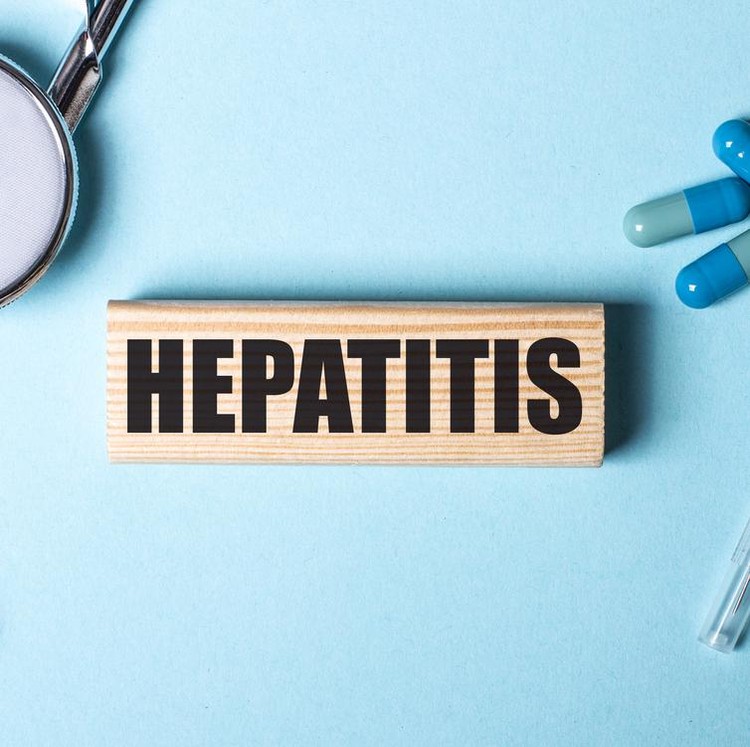 ilustrasi hepatitis misterius HEPATITIS written on a wooden block near a stethoscope, syringe and pills on a blue background. Medical concept
