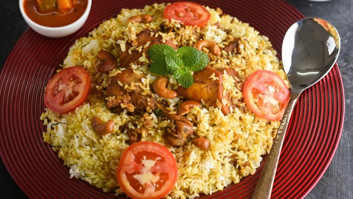 Kuzhimanthi or spicy Manthi Arabic chicken Biryani cooked meat, Basmati rice with spices in red plate on white background in Malabar Kerala, Karnataka South India. Top view of  Indian non veg food.