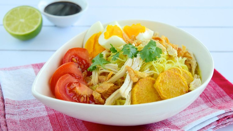 Soto Ayam, Indonesian food, yellow spicy chicken soup with vermicelli, tomato, fried potato, hard boiled egg and fried shallot.
