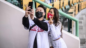 In this picture taken on April 20, 2022, Bae Soo-hyun (R), 37, South Korea's longest-serving cheerleader who has been performing with the SSG Landers team for nearly two decades, poses for a selfie with a fan before the team's match at the Incheon SS