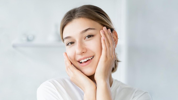 Natural beauty. Healthy skin. Dermatology hygiene. Cheerful smiling woman touching healthy fresh face on light defocused bathroom at morning.