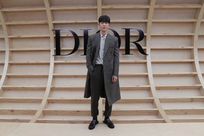 Gaya klasik ditampilkan Nam Joo Hyuk dengan kombinasi coat abu-abu dengan kemeja dan celana hitam. Foto: Getty Images for Dior/Myunggu Han