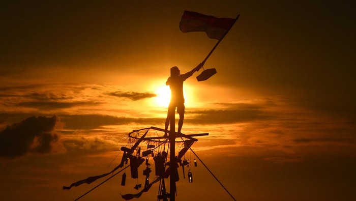 Warga mengibarkan bendera merah putih saat mengikuti lomba Panjat Pinang di kawasan Pantai Kelurahan Demaan, Jepara, Jawa Tengah, Senin (9/5/2022). Panjat Pinang tersebut untuk memeriahkan tradisi Syawalan atau Lebaran ketupat serta untuk menjalin kebersamaan dan menghibur warga. ANTARA FOTO/Yusuf Nugroho/pras.