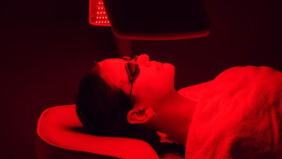 Young woman having red LED light facial therapy treatment in bea Young woman having red LED light facial therapy treatment in beauty salon. Beauty and wellness concept