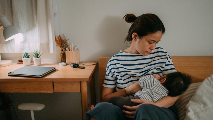 Happy mom and baby with a breastfeeding together in bedroom.