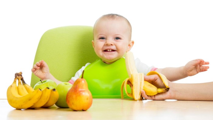 mother spoon feeding baby girl