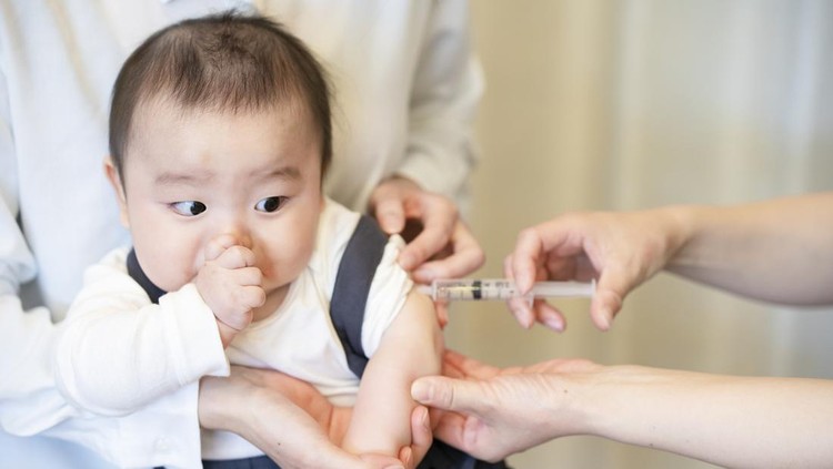 A baby who is vaccinated while being held by her mother