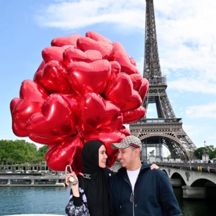 <p>Dengan senyum bahagia, Kartika dan suami berpose di depan Menara Eiffel sambil memebang puluhan balon berbentuk hati, Bunda. (Foto: Instagram: @kartikaputriworld)</p>