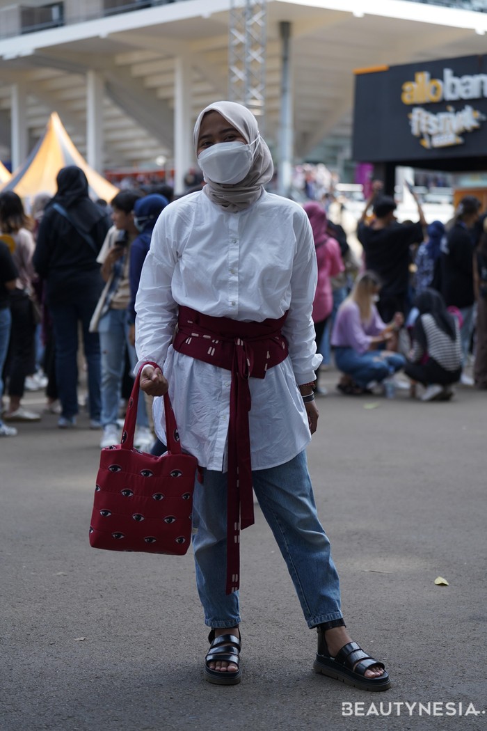 Padanan kasual kemeja putih dengan jeans jadi lebih stylish berkat padanan obi dan tas merah serta pilihan sporty sandals. Foto: Juluan Siagian