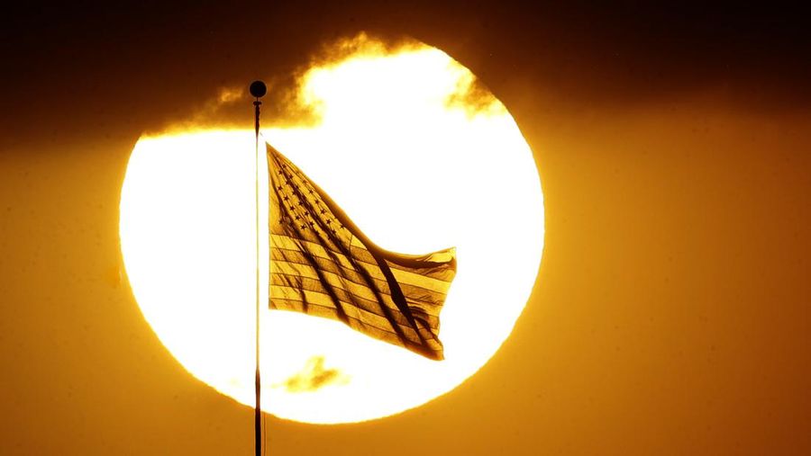 Bendera Amerika Serikat The United State flag is silhouetted against the setting sun Sunday, May 28, 2017, in Leavenworth, Kan. (AP Photo/Charlie Riedel)
