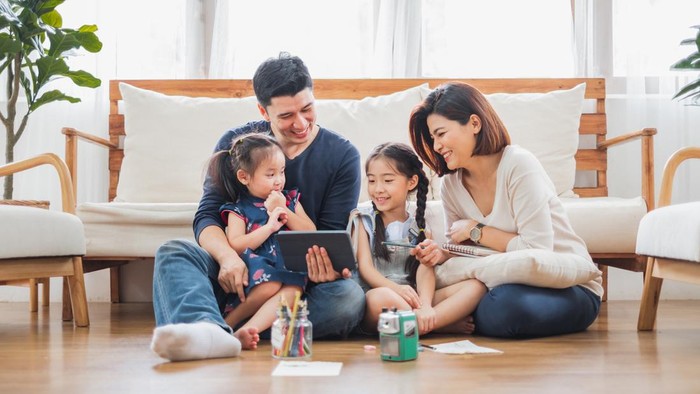 Happy Asian family using tablet, laptop for playing game watching movies, relaxing at home for lifestyle concept