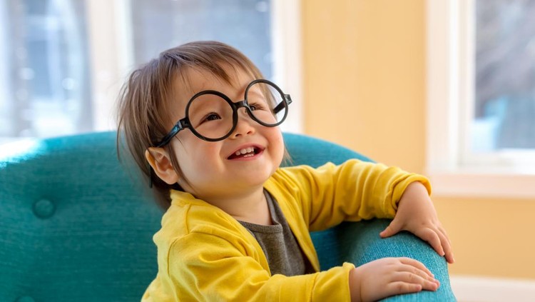Happy toddler boy with glasses playing in a big chair
