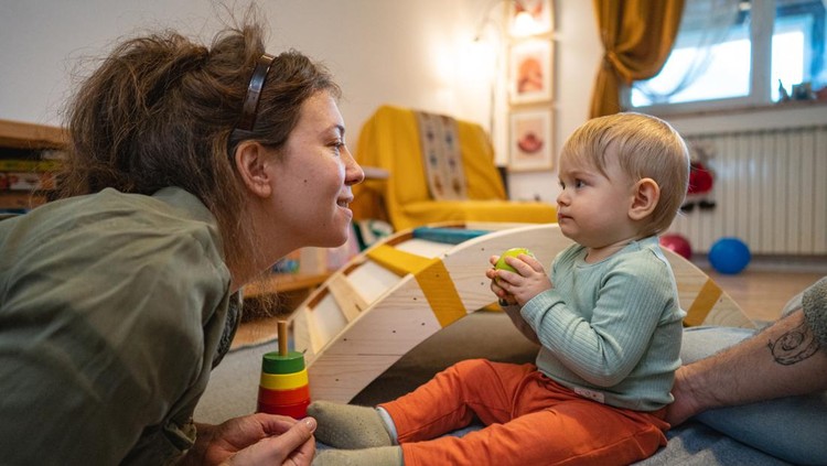 Lovely toodler boy playing with an apple, with his mother during playtime
