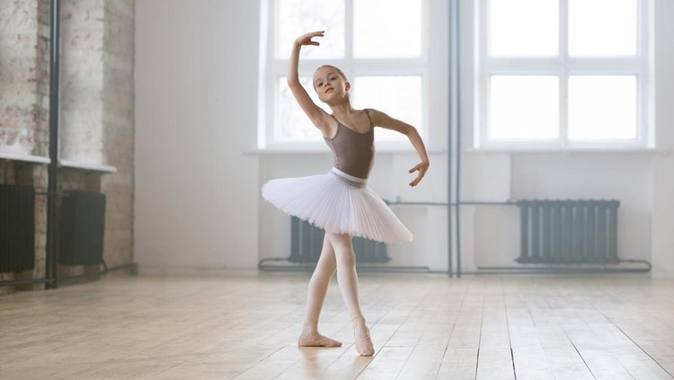 Portrait of little girl in tutu dress and shoes preparing for a ballet performance