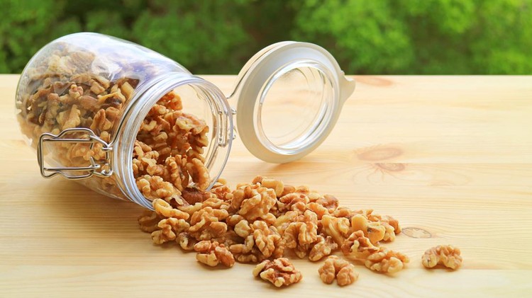 Ilustrasi Kacang Telur Heap of Walnut Kernels Scattered from a Glass Jar onto the Wooden Table