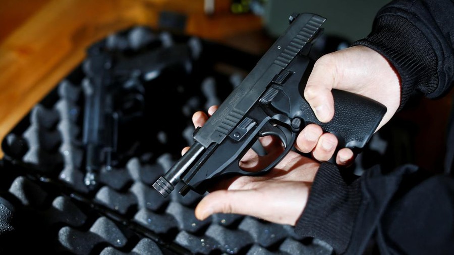 A legal owner poses with his 9mm Sig Sauer P239 after Canada's government introduced legislation to implement a 