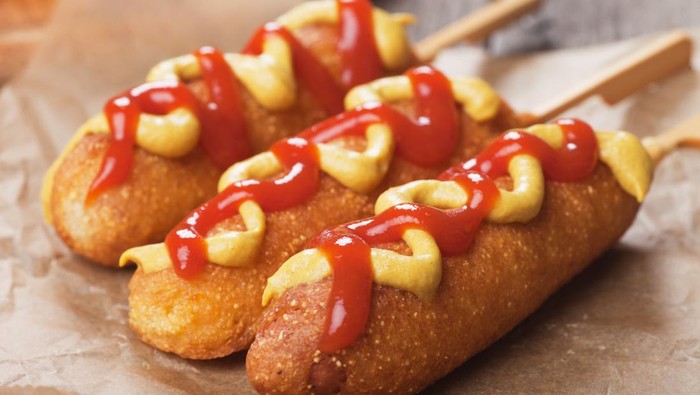 Corn dog, fried sausage in batter with mustard and ketchup