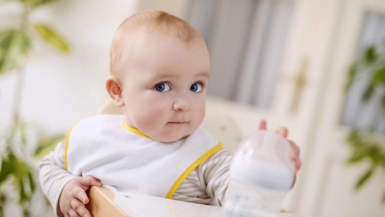 ilustrasi bayi A baby boy sitting in his high chair.He is holding a bottle in his hands.