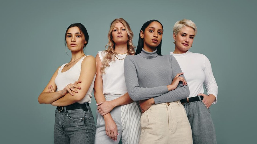 Group of fashionable women standing together in a studio. Diverse women looking at the camera while standing against a studio background. Four female friends looking confident in a studio.