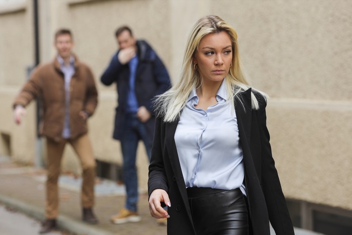 Two man yelling and finger whistling after a young beautiful woman. Young woman feeling anxiety and vulnerable. Two man yelling and finger whistling after a young beautiful woman. Young woman feeling anxiety and vulnerable.
