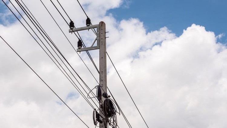 Small electric pole with the telephone cable under the clear blue sky.