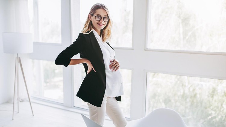 Attractive pregnant woman is working in light modern office. Feel of tiredness on last months of pregnancy.