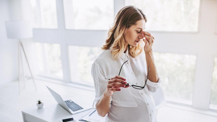 Attractive pregnant woman is working in light modern office. Feel of tiredness on last months of pregnancy.