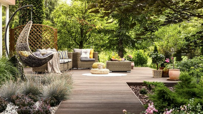 Beautiful wooden terrace with garden furniture surrounded by greenery on a warm, summer day
