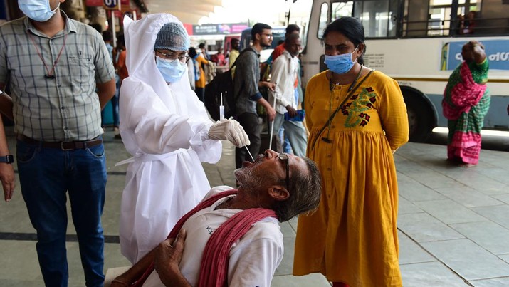 Seorang petugas kesehatan yang mengenakan pakaian mengambil sampel swab dari seorang penumpang untuk tes virus corona Covid-19 di sebuah terminal Bus di Ahmedabad pada 8 Juni 2022.. (AFP via Getty Images/SAM PANTHAKY)
