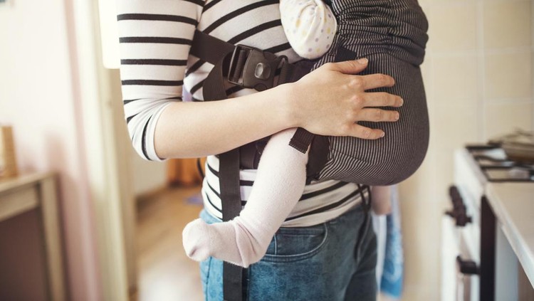 Young mother having her cute little daughter in baby carrier