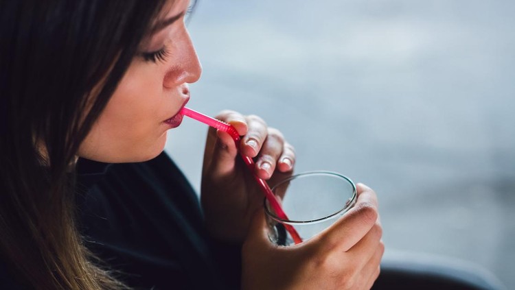 Portrait of young caucasian woman relaxing in cafe and drinking juice. Close up.