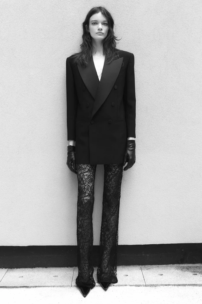 Selain stocking, kamu juga bisa mengenakan tuxedo dress atau oversized blazer dengan celana berbahan lace untuk tampilan yang seductive nan fierce.Foto: Courtesy of Saint Laurent
