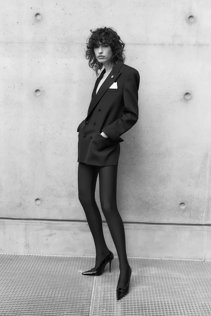 Tuxedo dress yang tak ubahnya hanya mengenakan blazer tanpa bawahan sedang jadi tren. Ide mix and match ala Saint Laurent yang mengenakannya bersama stocking bisa jadi alternatif agar lebih elegan. Foto: Courtesy of Saint Laurent