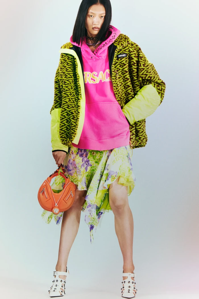 Mengapa tidak untuk mengombinasikan tiga motif sekaligus? Hoodie pink dengan jaket motif La Greca dengan floral dress jadi trik bergaya kasual dan bold di 2023 ala Versace. Foto: Courtesy of Versace