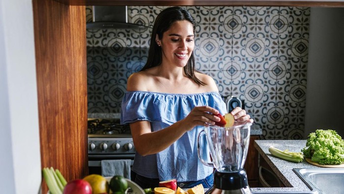 Latin Woman making green smoothie or Detox juice in kitchen at Home in healthy eating concept in Mexico