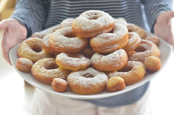 cropped female hand holding pile of donuts