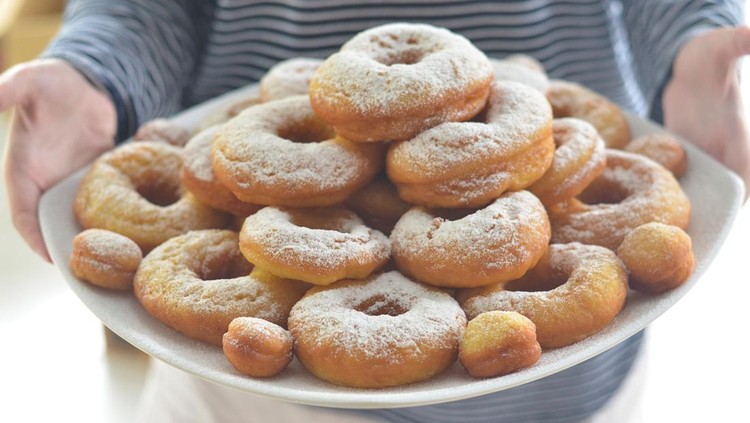 cropped female hand holding pile of donuts