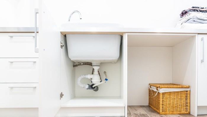 Under the sink view in laundry room with leak