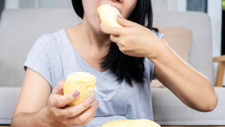 Asian woman overeating Durian fruit, unhealthy lifestyle concept